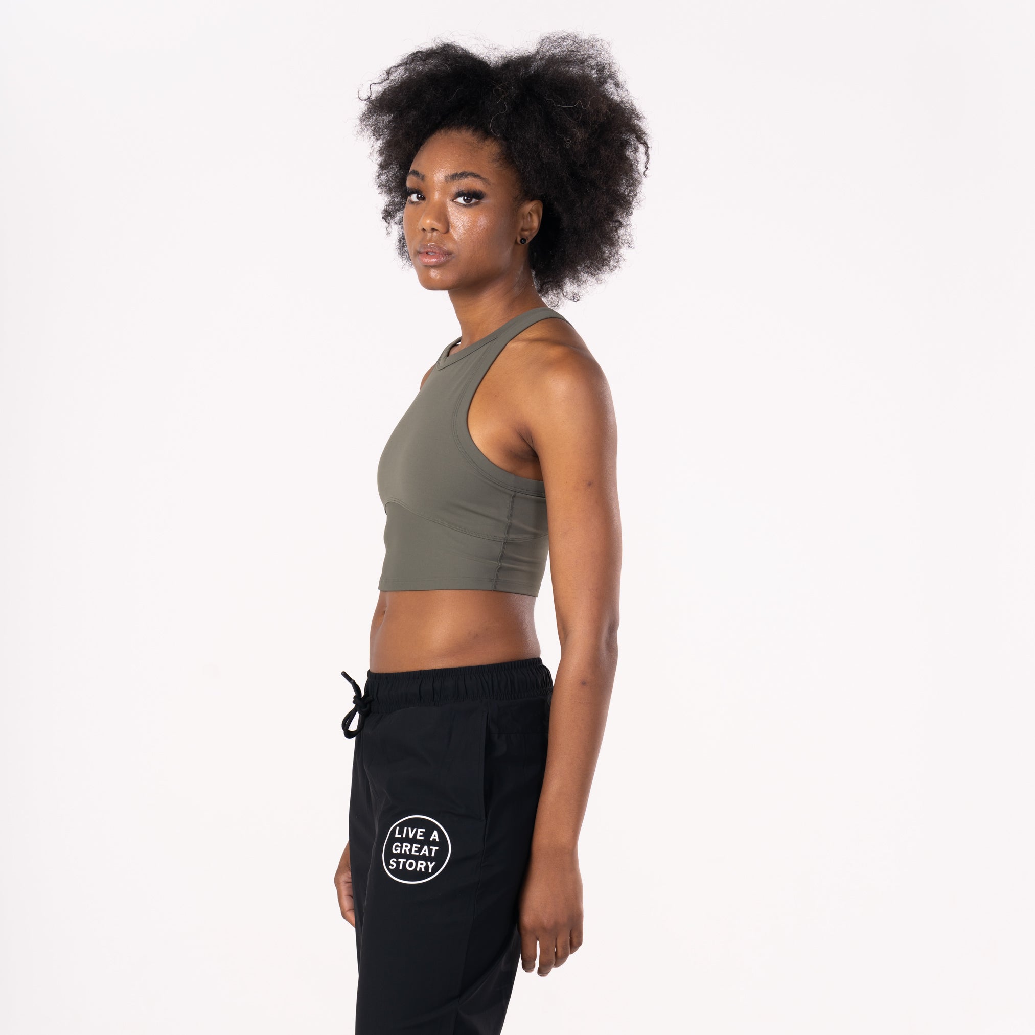 A woman wearing an olive LIVE A GREAT STORY women's tank top