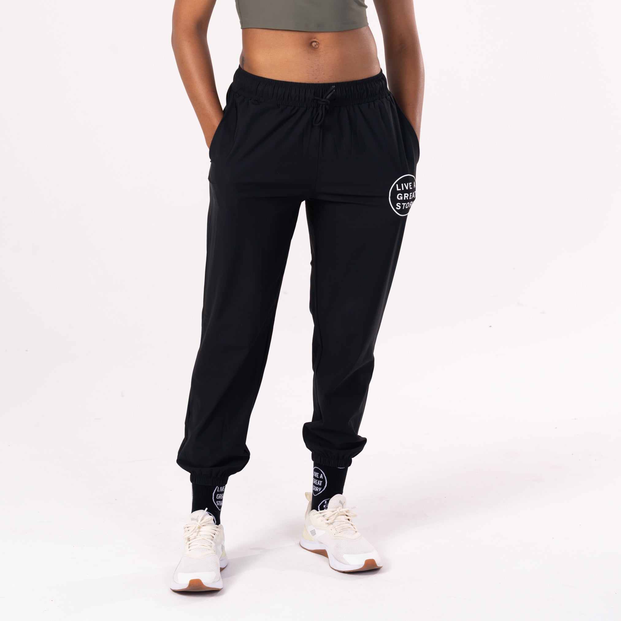 A woman wearing black LIVE A GREAT STORY athletic jogger pants