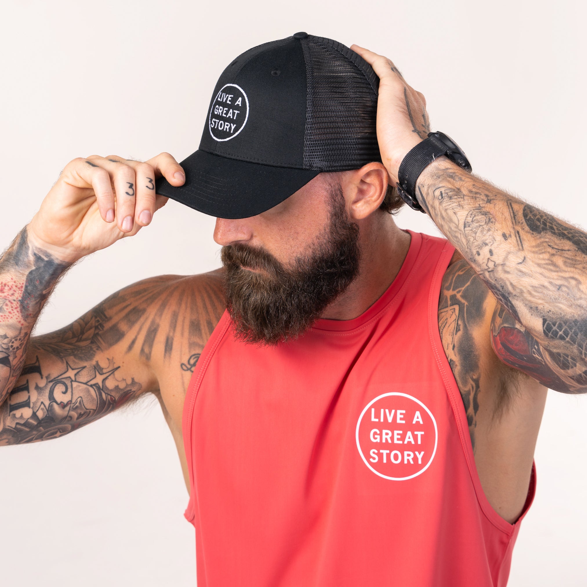 A man wearing a coral LIVE A GREAT STORY Men's Athletic Tank