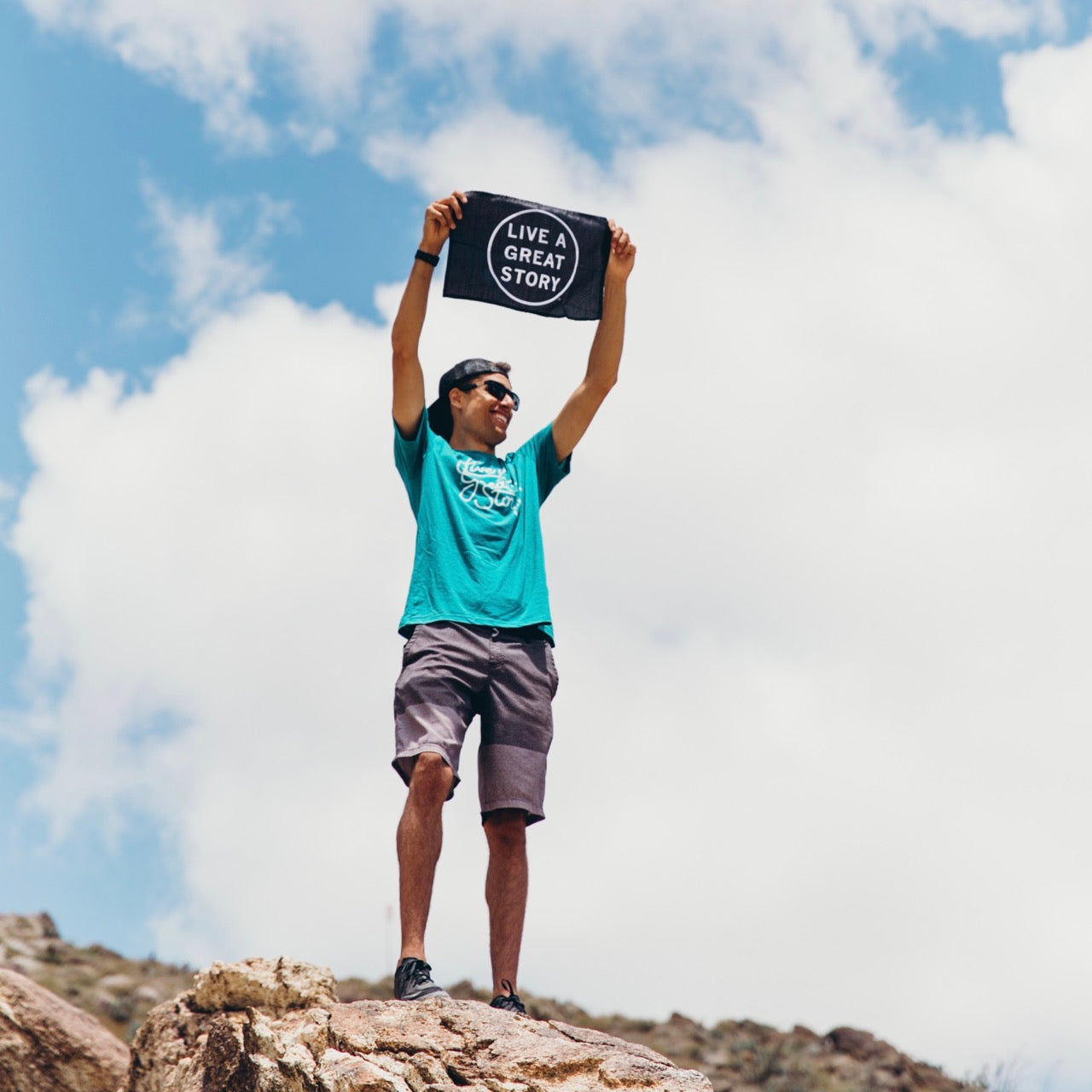 A person holding up a black LIVE A GREAT STORY Mini Adventure Flag