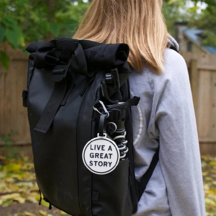 A LIVE A GREAT STORY luggage tag on a backpack