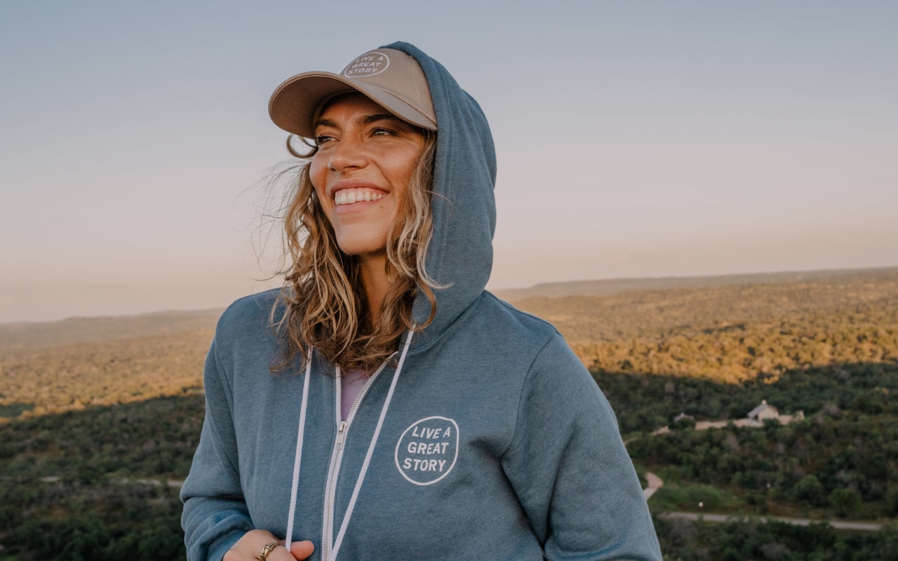 A woman wearing a LIVE A GREAT STORY hoodie