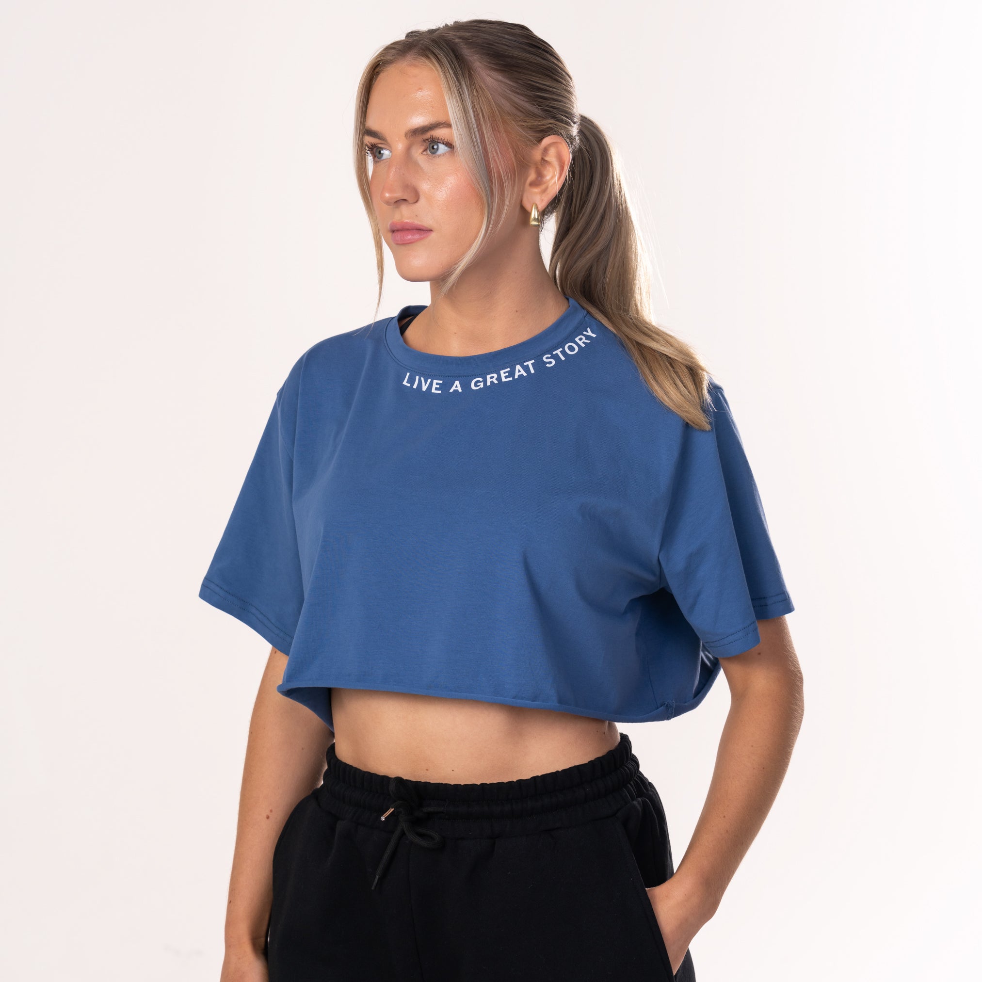 A woman wearing a blue LIVE A GREAT STORY women's crop top