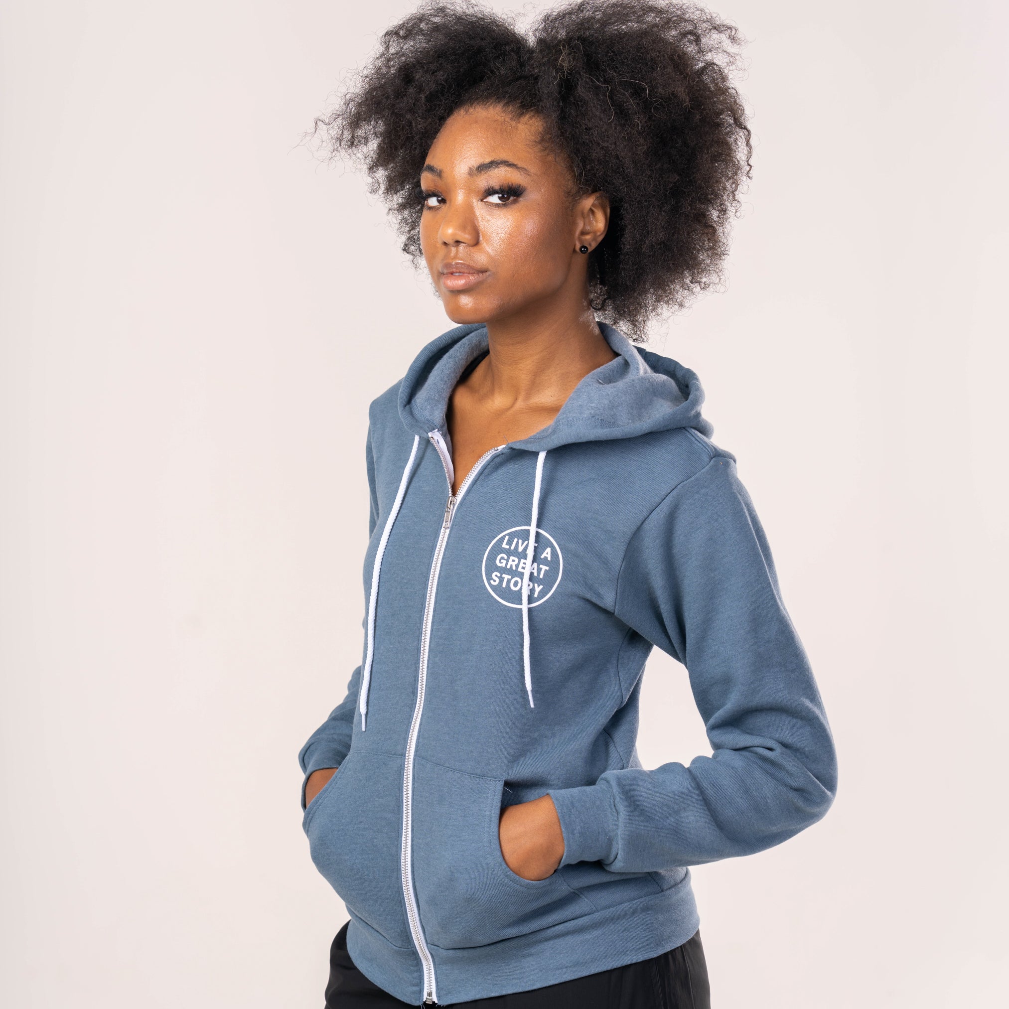 A person wearing a blue LIVE A GREAT STORY zip up hoodie