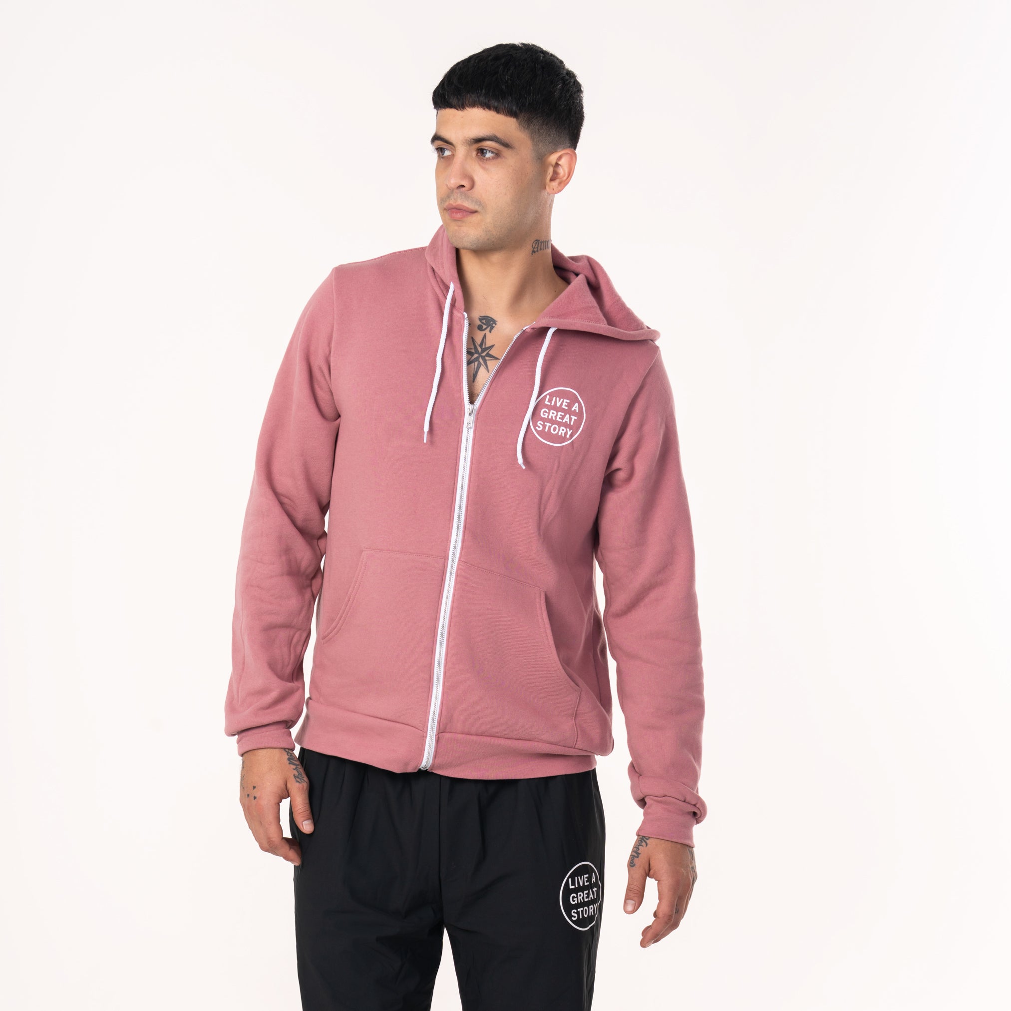 A person wearing a mauve LIVE A GREAT STORY zip up hoodie