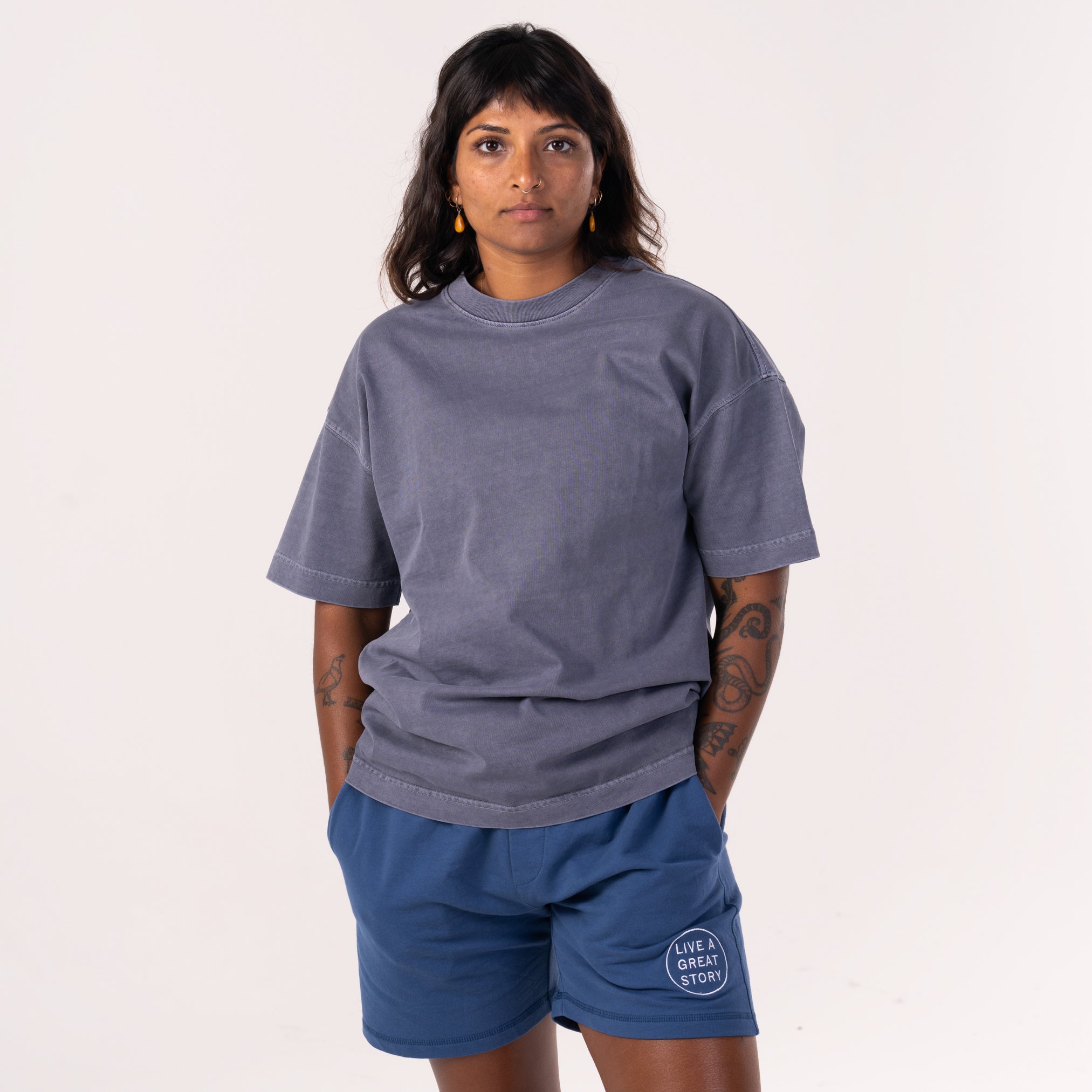 A woman wearing and showing the front view of a midnight gray LIVE A GREAT STORY Shoulder Print T-shirt