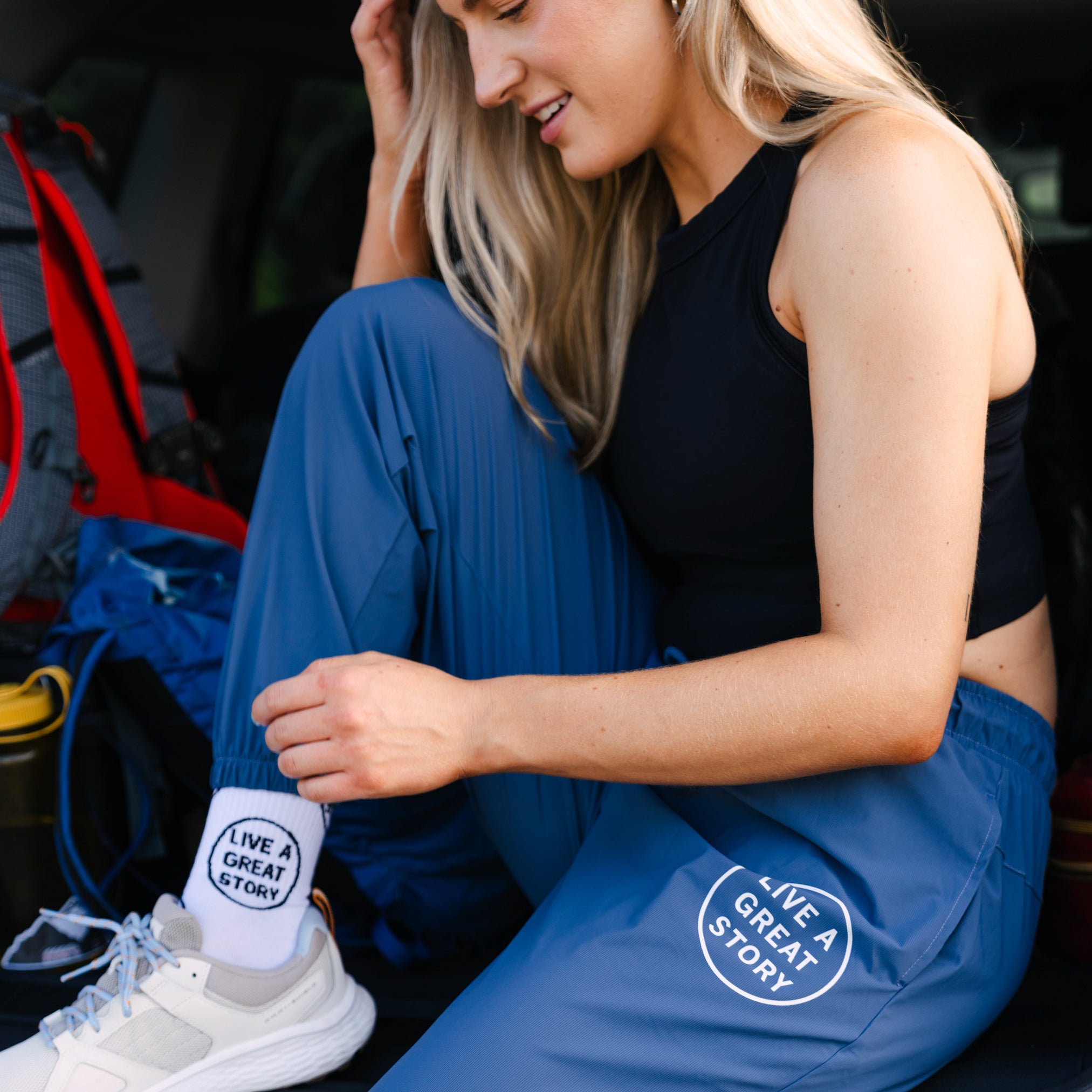 A woman wearing blue LIVE A GREAT STORY athletic jogger pants