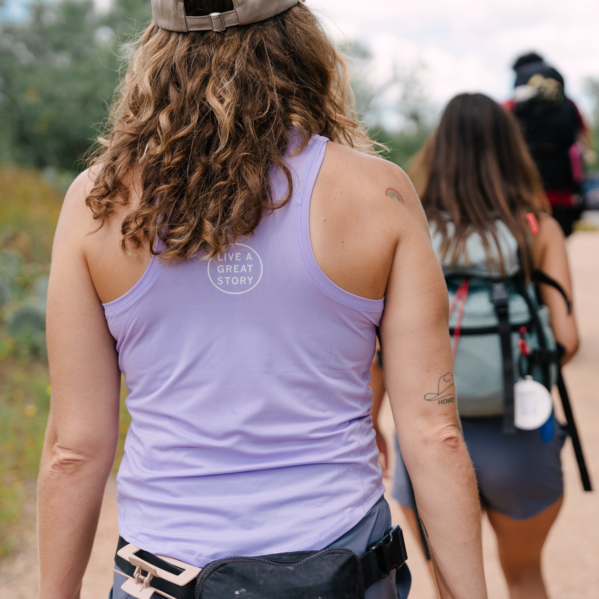 A woman wearing a lilac LIVE A GREAT STORY Women's Racer Tank Top while outdoors