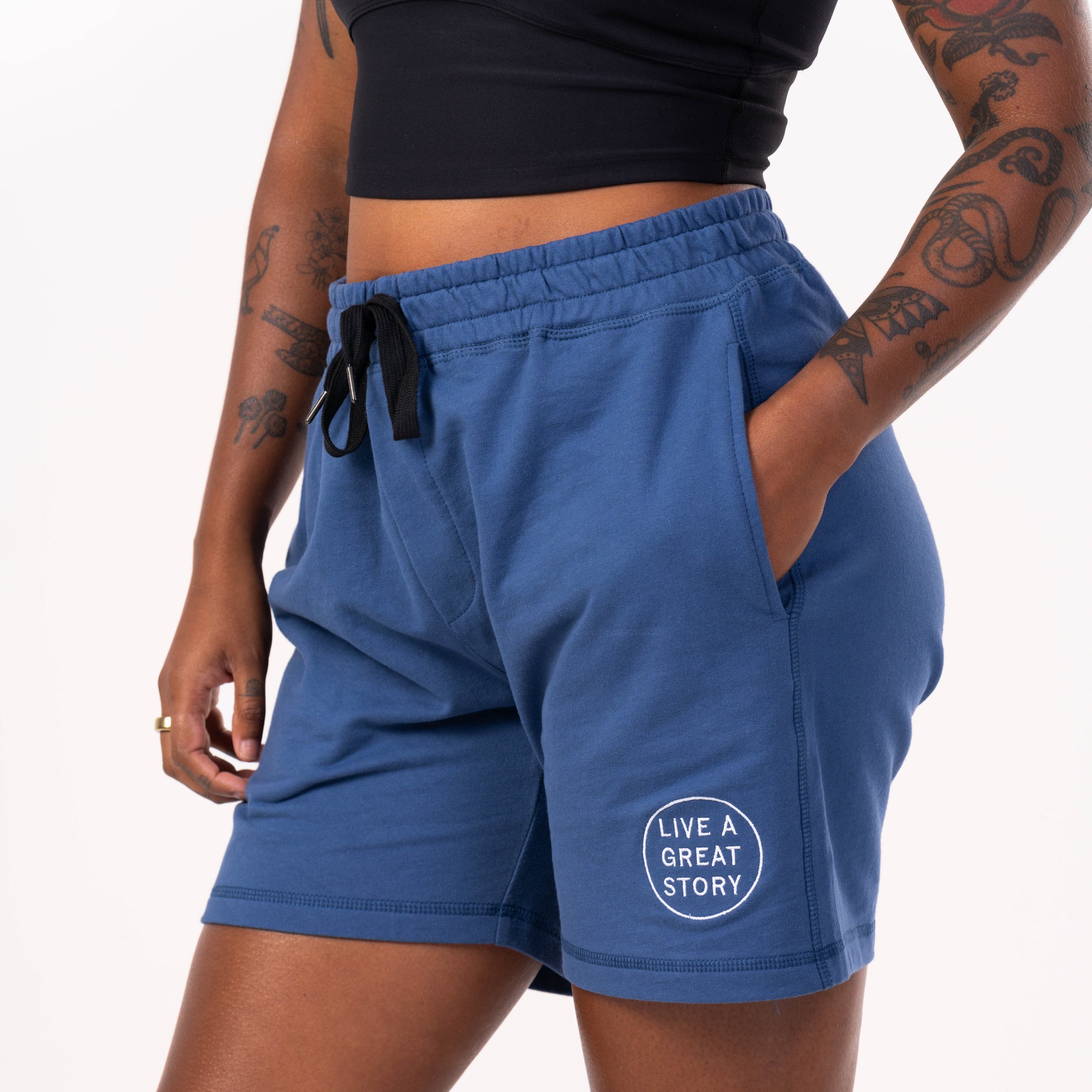 A closeup of a person wearing blue comfortable men's Camp Fire Shorts with their hand in the front pocket