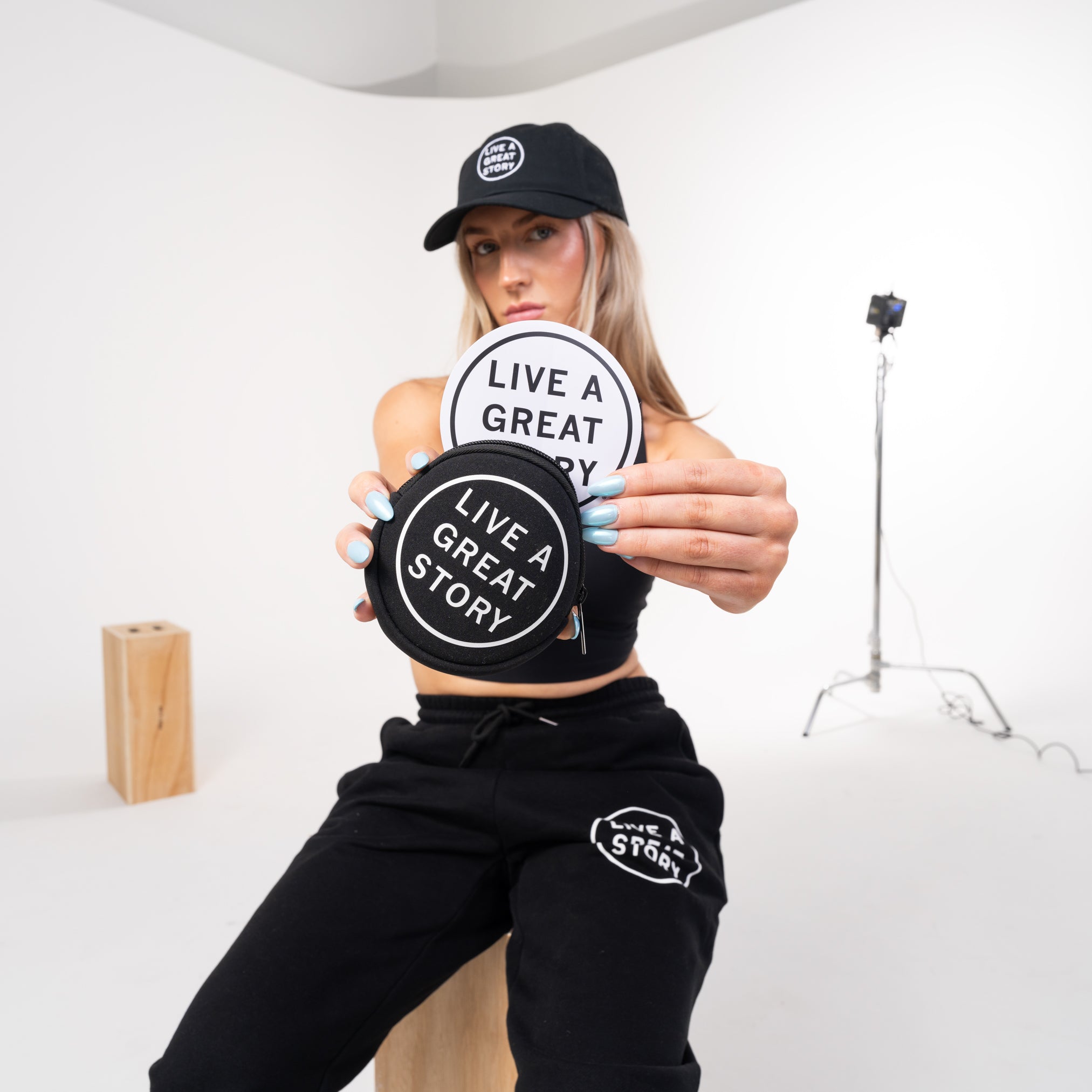 A  woman holding a LIVE A GREAT STORY coin pouch with stickers in it