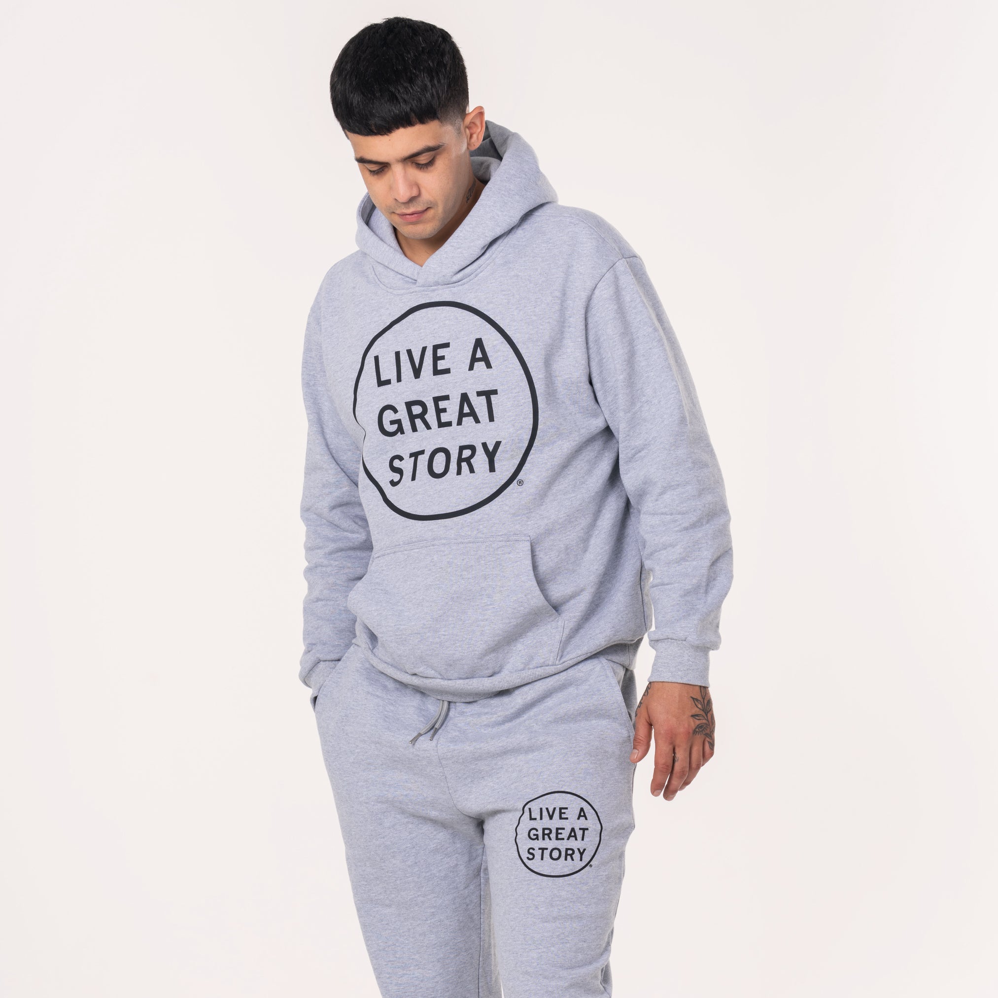 A person wearing a light gray LIVE A GREAT STORY original 100% cotton hoodie
