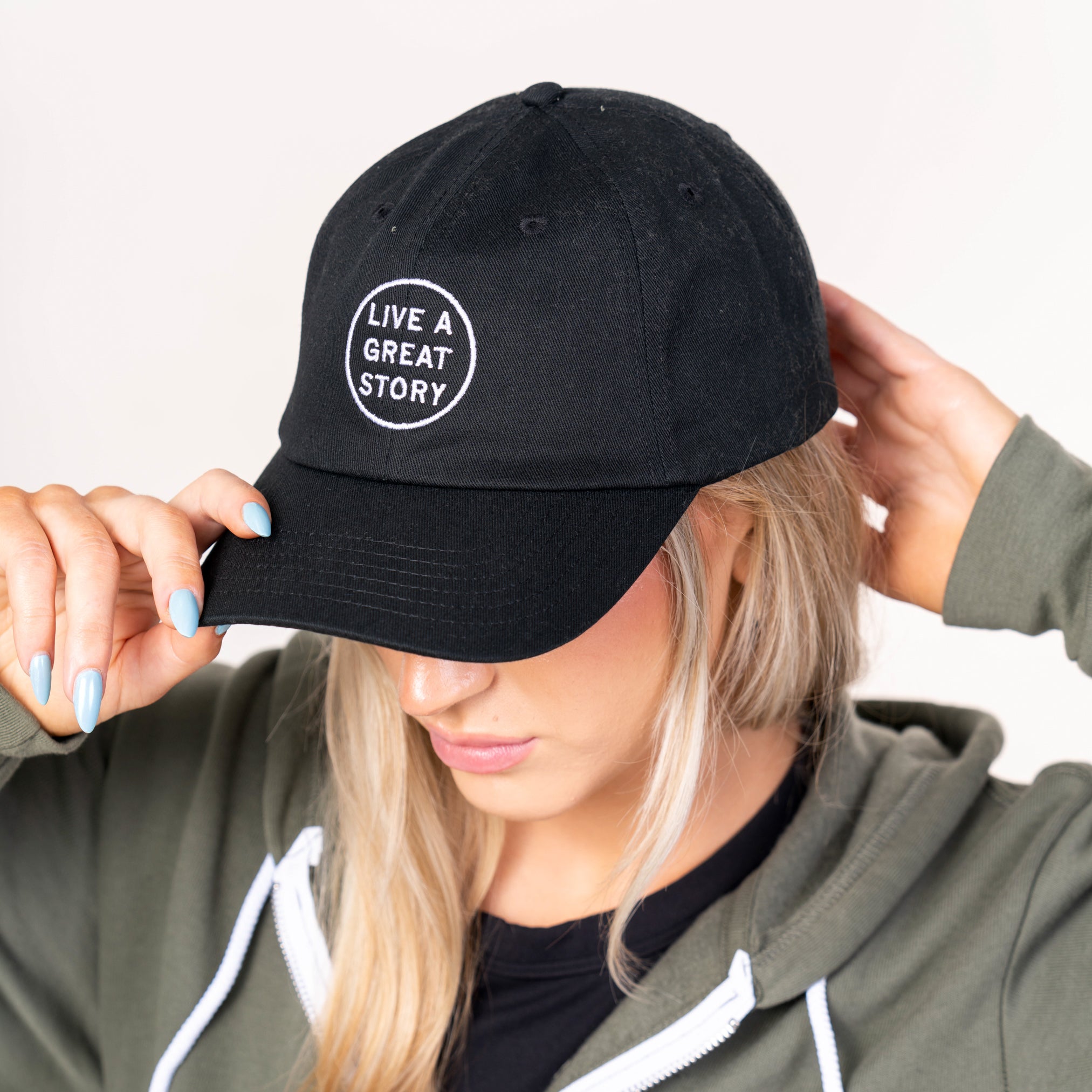 A woman wearing a black LIVE A GREAT STORY Dad Hat