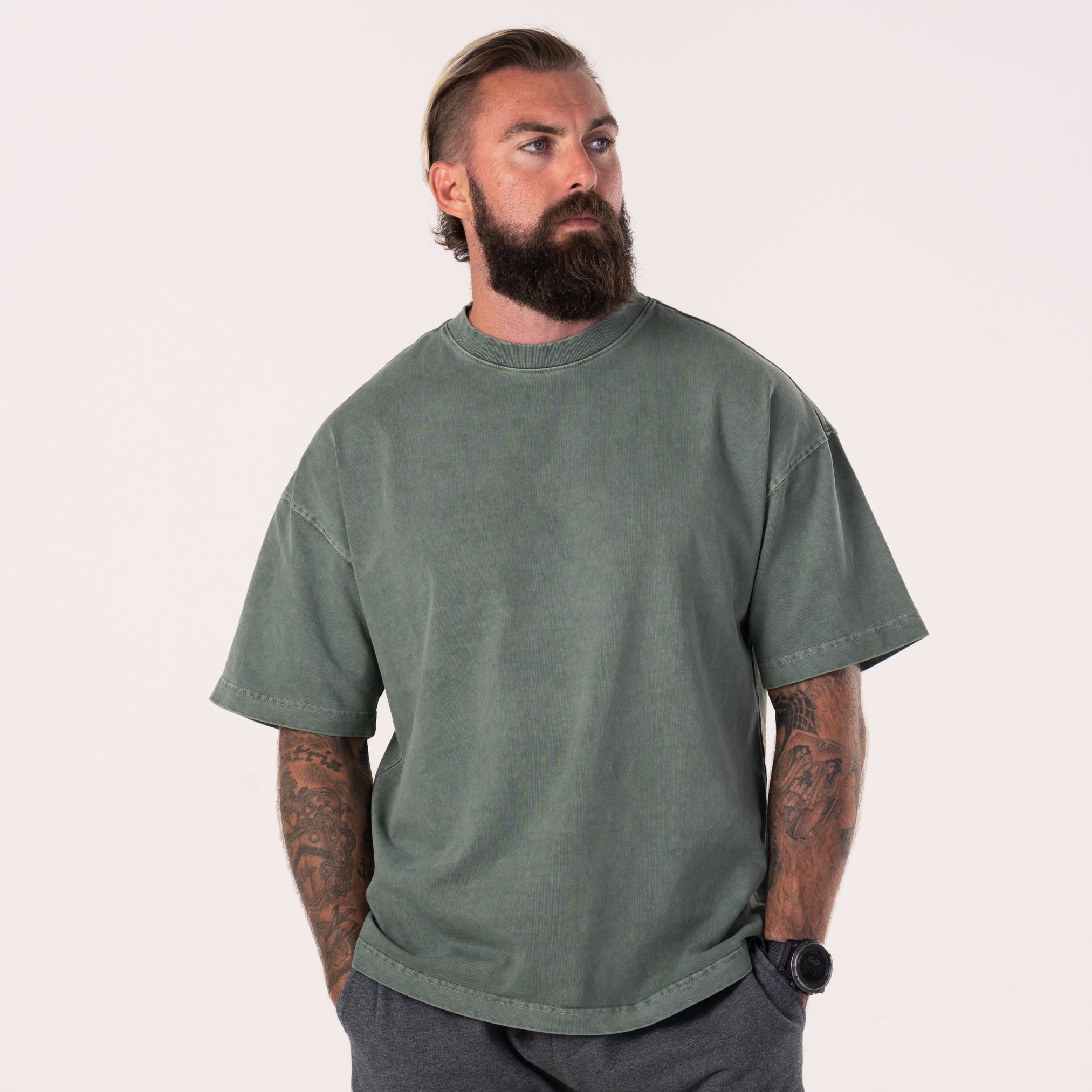 A man wearing and showing the front view of a forest green LIVE A GREAT STORY Shoulder Print T-shirt