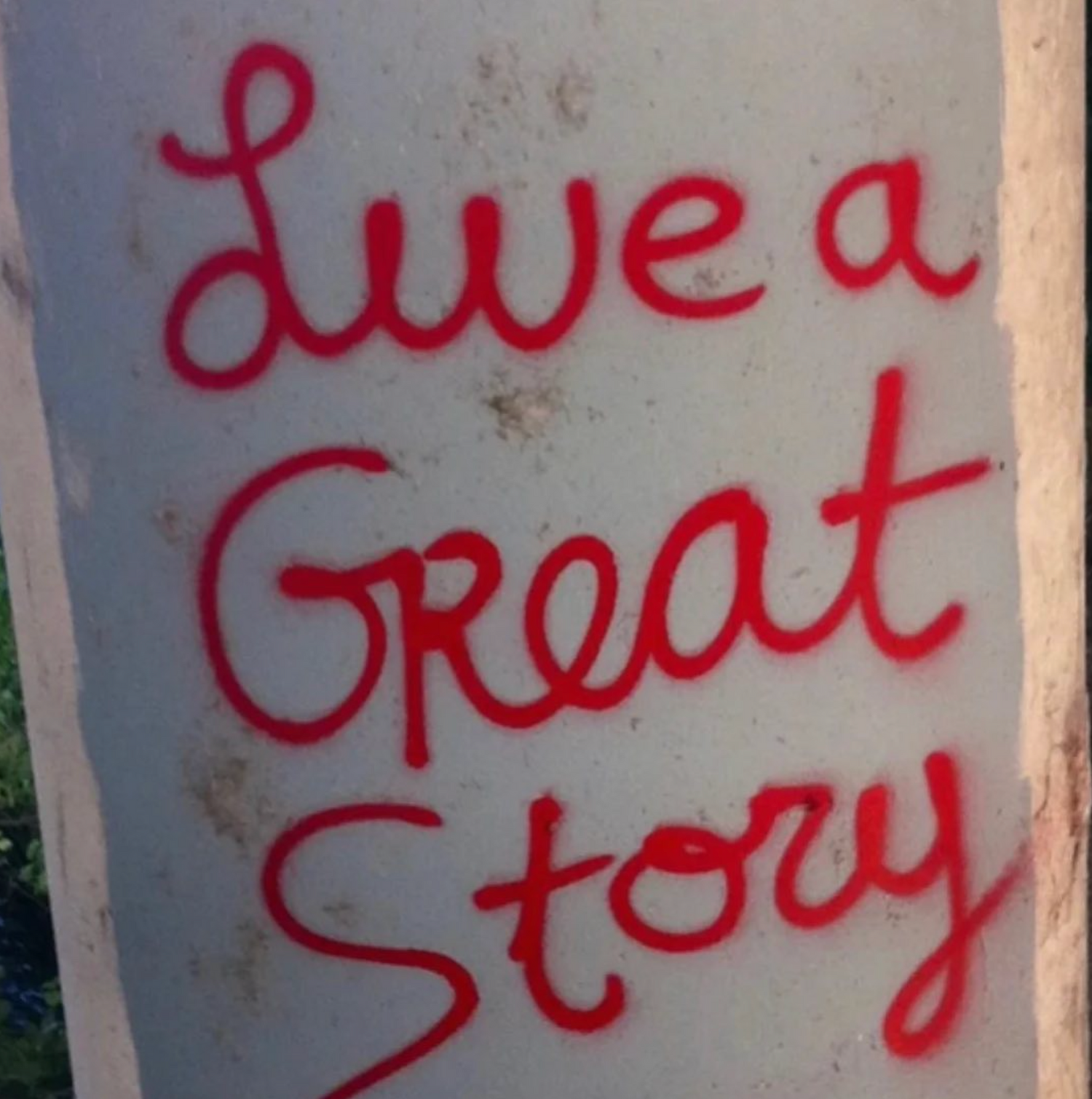 The original LIVE A GREAT STORY quote in red spray paint
