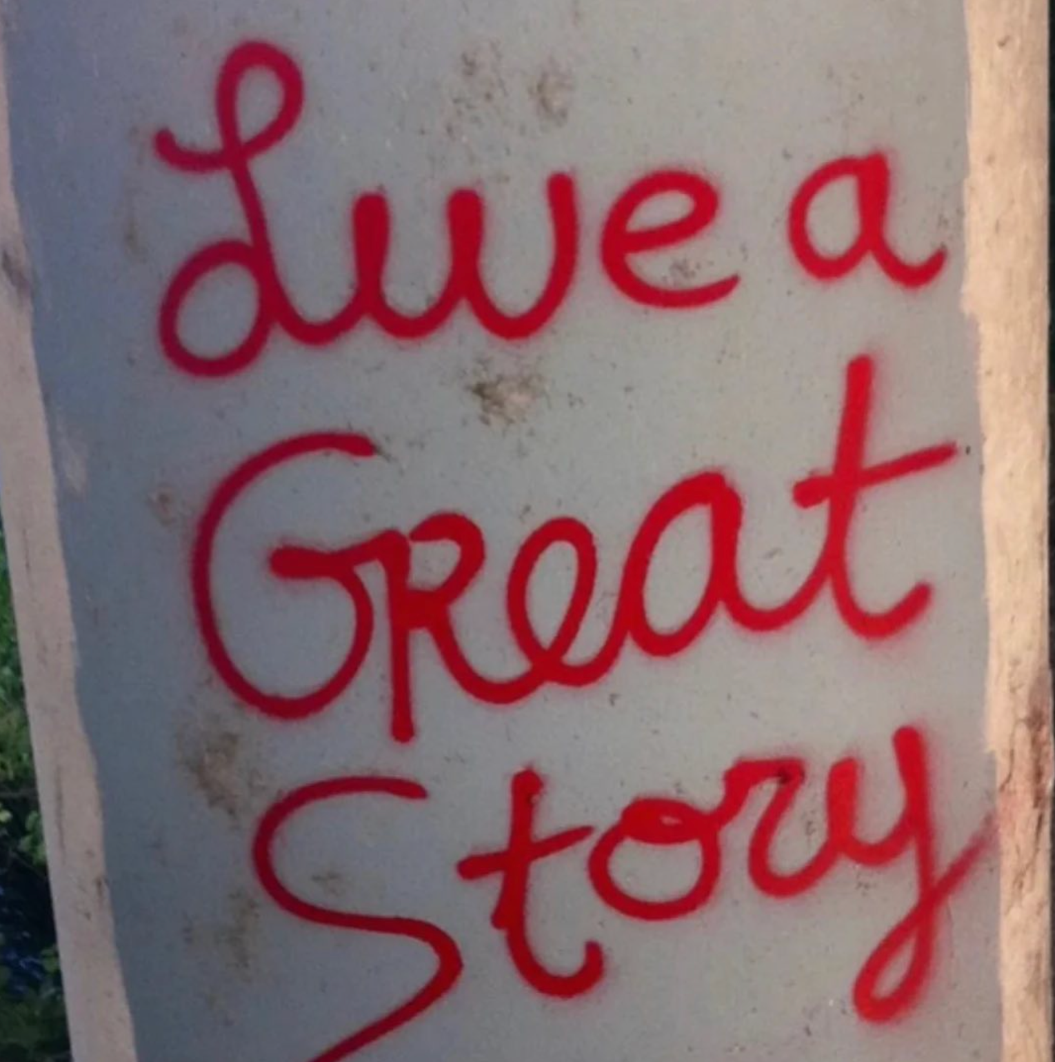 The original LIVE A GREAT STORY quote in red spray paint