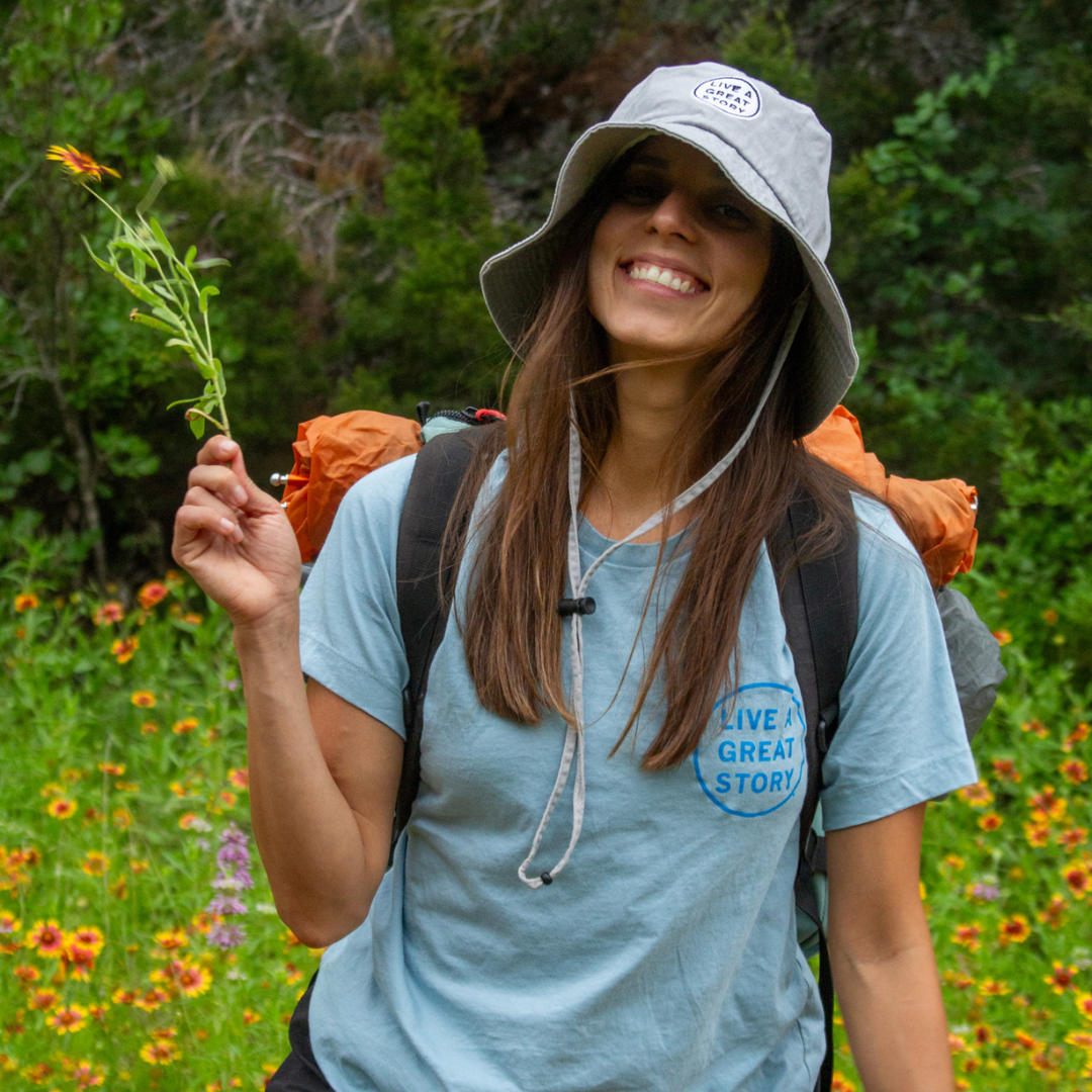 A woman wearing a light blue LIVE A GREAT STORY 100% cotton chest print T-shirt while outside