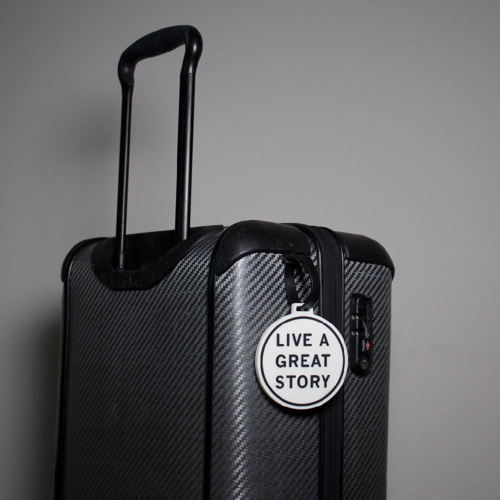 A LIVE A GREAT STORY luggage tag on a travel suitcase